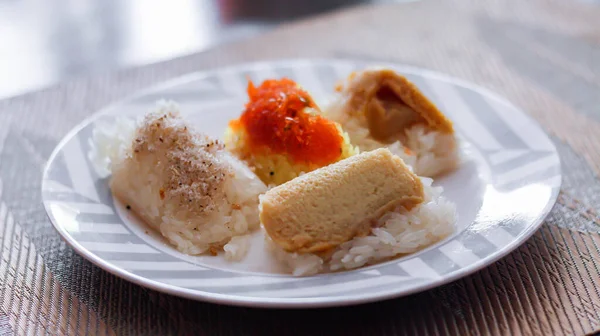 3 flavors Thai desserts, sticky rice, custard topped with dried fish and yellow sticky rice, wrapped in banana leaves in thailand.