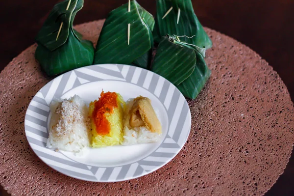 3 flavors Thai desserts, sticky rice, custard topped with dried fish and yellow sticky rice, wrapped in banana leaves in thailand.