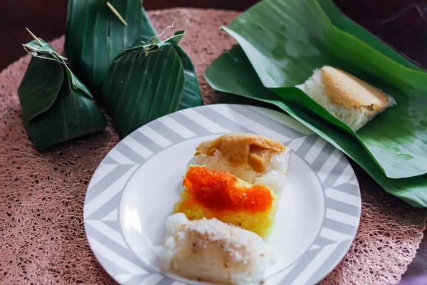 3 flavors Thai desserts, sticky rice, custard topped with dried fish and yellow sticky rice, wrapped in banana leaves in thailand.