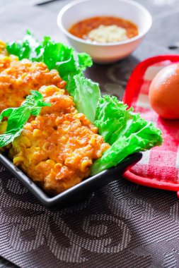 Siyah ahşap bir masaya konmuş acı biber soslu mısır cipsi.