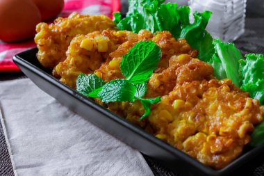 Siyah ahşap bir masaya konmuş acı biber soslu mısır cipsi.