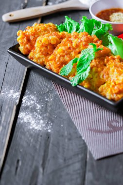 Siyah ahşap bir masaya konmuş acı biber soslu mısır cipsi.