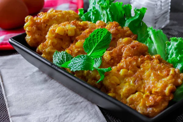 Siyah ahşap bir masaya konmuş acı biber soslu mısır cipsi.