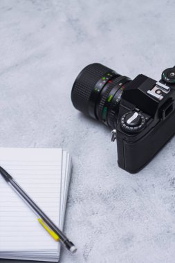 Film kameraları, güneş gözlükleri ve eskiz defterleri seyahate hazırlanmak için beyaz bir masaya yerleştirildi..