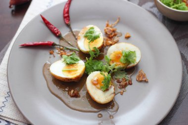 Tahta bir masada kişniş parçacıkları ile servis edilen Tamarind soslu yumurta Taylandlıların yediği popüler bir yerel yemektir..