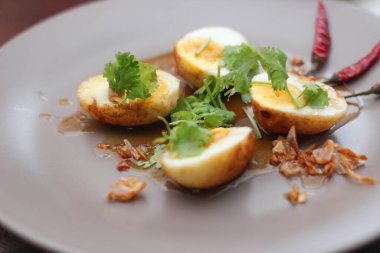 Tahta bir masada kişniş parçacıkları ile servis edilen Tamarind soslu yumurta Taylandlıların yediği popüler bir yerel yemektir..