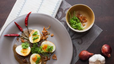 Tahta bir masada kişniş parçacıkları ile servis edilen Tamarind soslu yumurta Taylandlıların yediği popüler bir yerel yemektir..