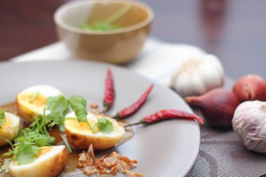 Tahta bir masada kişniş parçacıkları ile servis edilen Tamarind soslu yumurta Taylandlıların yediği popüler bir yerel yemektir..