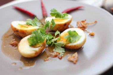 Tahta bir masada kişniş parçacıkları ile servis edilen Tamarind soslu yumurta Taylandlıların yediği popüler bir yerel yemektir..