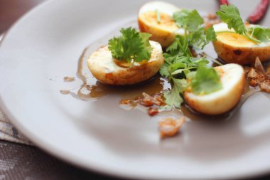 Tahta bir masada kişniş parçacıkları ile servis edilen Tamarind soslu yumurta Taylandlıların yediği popüler bir yerel yemektir..