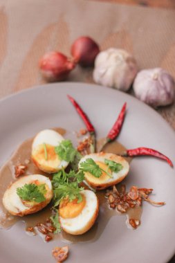 Tahta bir masada kişniş parçacıkları ile servis edilen Tamarind soslu yumurta Taylandlıların yediği popüler bir yerel yemektir..