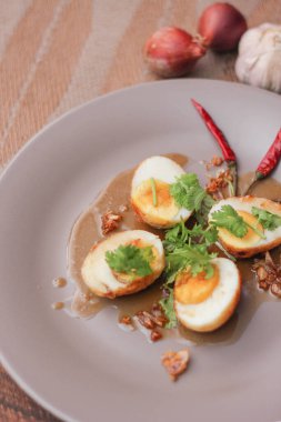Tahta bir masada kişniş parçacıkları ile servis edilen Tamarind soslu yumurta Taylandlıların yediği popüler bir yerel yemektir..