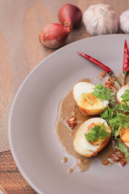 Tahta bir masada kişniş parçacıkları ile servis edilen Tamarind soslu yumurta Taylandlıların yediği popüler bir yerel yemektir..