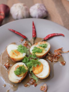 Tahta bir masada kişniş parçacıkları ile servis edilen Tamarind soslu yumurta Taylandlıların yediği popüler bir yerel yemektir..