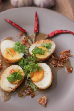 Tahta bir masada kişniş parçacıkları ile servis edilen Tamarind soslu yumurta Taylandlıların yediği popüler bir yerel yemektir..