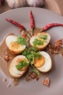 Tahta bir masada kişniş parçacıkları ile servis edilen Tamarind soslu yumurta Taylandlıların yediği popüler bir yerel yemektir..