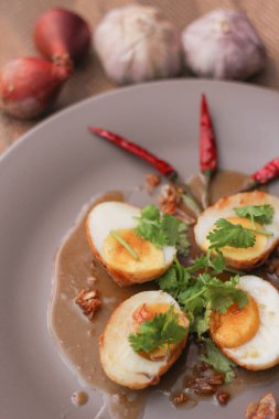 Tahta bir masada kişniş parçacıkları ile servis edilen Tamarind soslu yumurta Taylandlıların yediği popüler bir yerel yemektir..