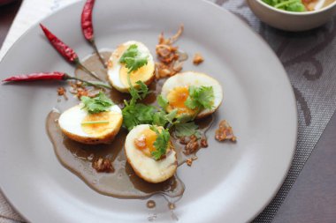 Tahta bir masada kişniş parçacıkları ile servis edilen Tamarind soslu yumurta Taylandlıların yediği popüler bir yerel yemektir..