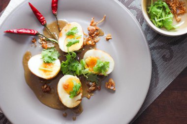 Tahta bir masada kişniş parçacıkları ile servis edilen Tamarind soslu yumurta Taylandlıların yediği popüler bir yerel yemektir..