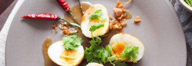 Tahta bir masada kişniş parçacıkları ile servis edilen Tamarind soslu yumurta Taylandlıların yediği popüler bir yerel yemektir..