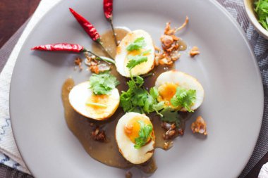 Tahta bir masada kişniş parçacıkları ile servis edilen Tamarind soslu yumurta Taylandlıların yediği popüler bir yerel yemektir..