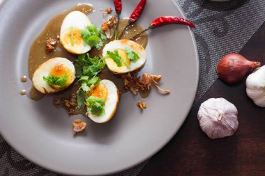 Tahta bir masada kişniş parçacıkları ile servis edilen Tamarind soslu yumurta Taylandlıların yediği popüler bir yerel yemektir..