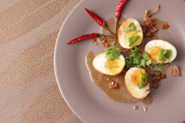 Tahta bir masada kişniş parçacıkları ile servis edilen Tamarind soslu yumurta Taylandlıların yediği popüler bir yerel yemektir..