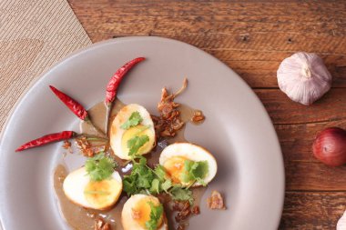 Tahta bir masada kişniş parçacıkları ile servis edilen Tamarind soslu yumurta Taylandlıların yediği popüler bir yerel yemektir..