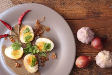 Tahta bir masada kişniş parçacıkları ile servis edilen Tamarind soslu yumurta Taylandlıların yediği popüler bir yerel yemektir..