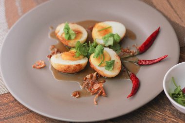 Tahta bir masada kişniş parçacıkları ile servis edilen Tamarind soslu yumurta Taylandlıların yediği popüler bir yerel yemektir..