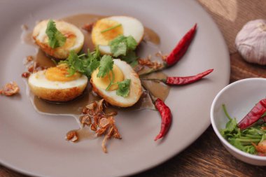 Tahta bir masada kişniş parçacıkları ile servis edilen Tamarind soslu yumurta Taylandlıların yediği popüler bir yerel yemektir..