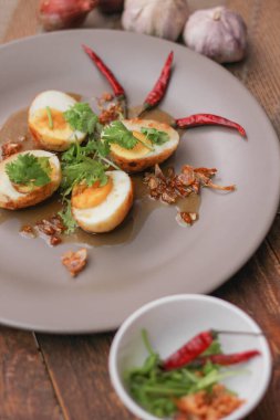 Tahta bir masada kişniş parçacıkları ile servis edilen Tamarind soslu yumurta Taylandlıların yediği popüler bir yerel yemektir..