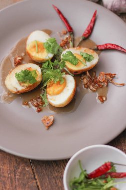 Tahta bir masada kişniş parçacıkları ile servis edilen Tamarind soslu yumurta Taylandlıların yediği popüler bir yerel yemektir..