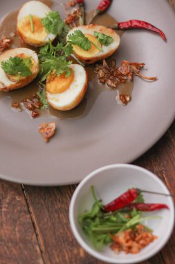 Tahta bir masada kişniş parçacıkları ile servis edilen Tamarind soslu yumurta Taylandlıların yediği popüler bir yerel yemektir..