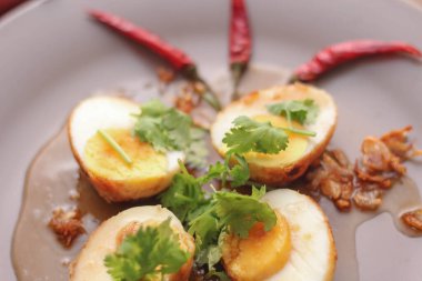 Tahta bir masada kişniş parçacıkları ile servis edilen Tamarind soslu yumurta Taylandlıların yediği popüler bir yerel yemektir..