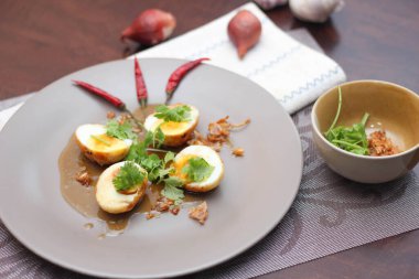 Tahta bir masada kişniş parçacıkları ile servis edilen Tamarind soslu yumurta Taylandlıların yediği popüler bir yerel yemektir..