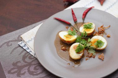 Tahta bir masada kişniş parçacıkları ile servis edilen Tamarind soslu yumurta Taylandlıların yediği popüler bir yerel yemektir..