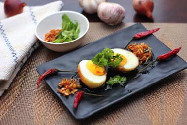 Tahta bir masada kişniş parçacıkları ile servis edilen Tamarind soslu yumurta Taylandlıların yediği popüler bir yerel yemektir..
