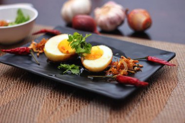 Tahta bir masada kişniş parçacıkları ile servis edilen Tamarind soslu yumurta Taylandlıların yediği popüler bir yerel yemektir..