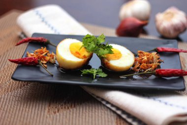 Tahta bir masada kişniş parçacıkları ile servis edilen Tamarind soslu yumurta Taylandlıların yediği popüler bir yerel yemektir..