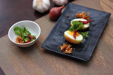 Tahta bir masada kişniş parçacıkları ile servis edilen Tamarind soslu yumurta Taylandlıların yediği popüler bir yerel yemektir..