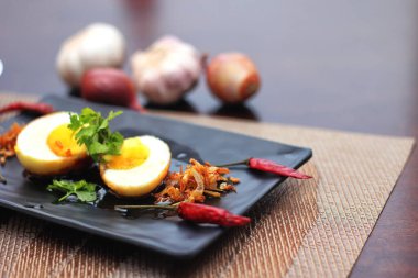 Tahta bir masada kişniş parçacıkları ile servis edilen Tamarind soslu yumurta Taylandlıların yediği popüler bir yerel yemektir..
