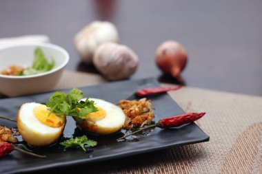 Tahta bir masada kişniş parçacıkları ile servis edilen Tamarind soslu yumurta Taylandlıların yediği popüler bir yerel yemektir..