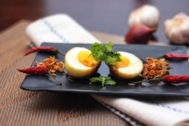 Tahta bir masada kişniş parçacıkları ile servis edilen Tamarind soslu yumurta Taylandlıların yediği popüler bir yerel yemektir..