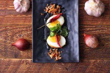 Tahta bir masada kişniş parçacıkları ile servis edilen Tamarind soslu yumurta Taylandlıların yediği popüler bir yerel yemektir..