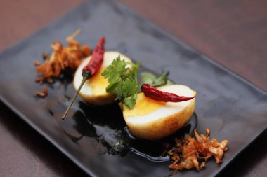 Tahta bir masada kişniş parçacıkları ile servis edilen Tamarind soslu yumurta Taylandlıların yediği popüler bir yerel yemektir..