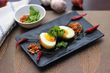 Tahta bir masada kişniş parçacıkları ile servis edilen Tamarind soslu yumurta Taylandlıların yediği popüler bir yerel yemektir..