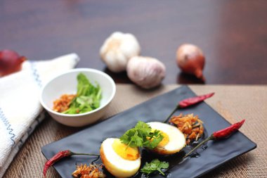 Tahta bir masada kişniş parçacıkları ile servis edilen Tamarind soslu yumurta Taylandlıların yediği popüler bir yerel yemektir..