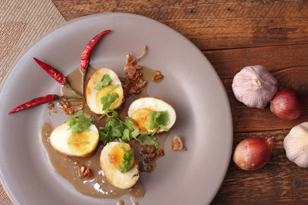 Tahta bir masada kişniş parçacıkları ile servis edilen Tamarind soslu yumurta Taylandlıların yediği popüler bir yerel yemektir..