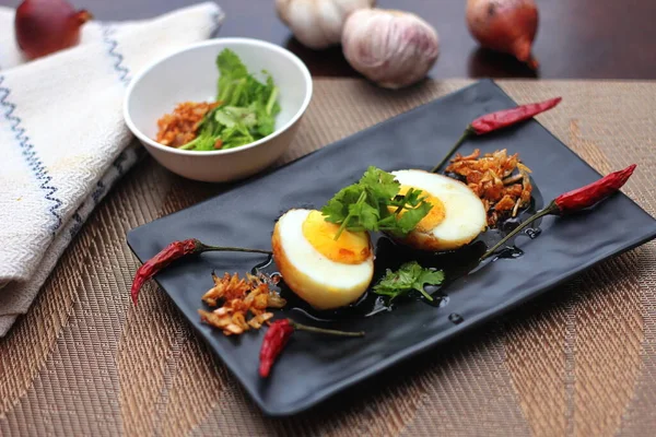 Tahta bir masada kişniş parçacıkları ile servis edilen Tamarind soslu yumurta Taylandlıların yediği popüler bir yerel yemektir..
